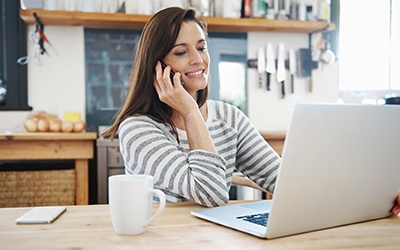 Woman looking at dental insurance information and talking on phone