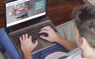 Man looking at dental insurance options on laptop computer