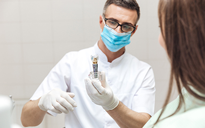 Dentist showing patient an implant model