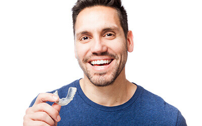 Man smiling holding Invisalign